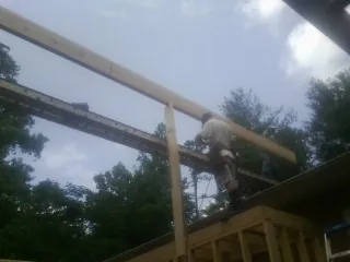 Carpenter setting a ridge beam over a new addition frame — Ice Dam Removal by Roofing Brothers in Lumpkin