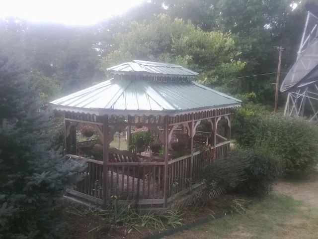 Green metal roof on a backyard gazebo surrounded by garden beds in Lumpkin