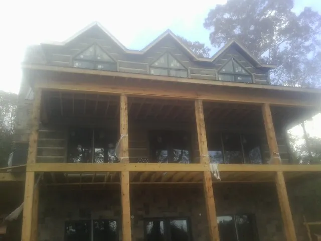 Dormers and porch framing on a large log home under construction — Roof Coating work by our crew in Lumpkin