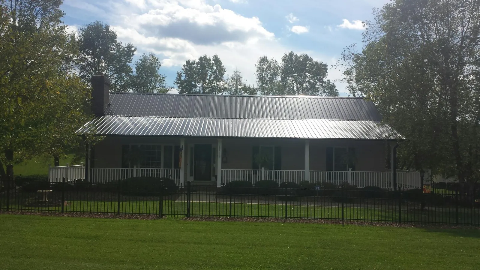 Gray metal roof on a brick ranch with a full width front porch — Gutter Guard Installation work by our crew in Lumpkin