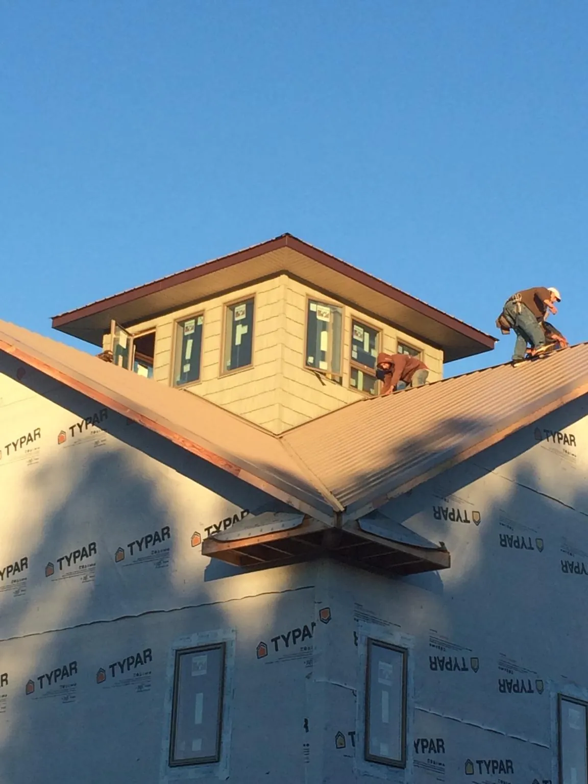Roofers working around a rooftop cupola on a new metal roof at sunset — Roof Waterproofing in Lumpkin by Roofing Brothers